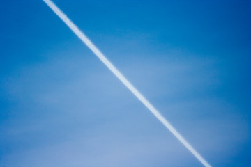 streak of an airplane flying in the clear blue sky