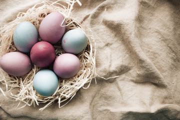 Painted Easter eggs in nest on sackcloth, rustic festive composition