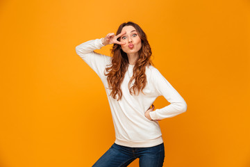 Funny brunette woman in sweater posing with arm on hip