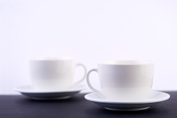 Two white porcelain teacups on black table show clean and simple design ideas, selective focus