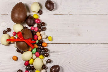 Easter composition with chocolate eggs on white wooden background