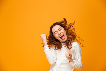 Happy screaming brunette woman in sweater rejoices with closed eyes