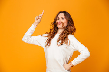 Joyful woman in sweater with arm on hip showing forefinger