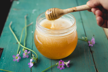 Honey in a glass bottle On blue wood in low light