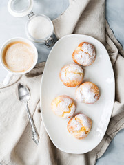 Cakes profiteroles sprinkled with powdered sugar served on white plate