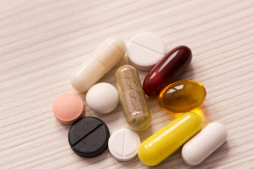 The pills are scattered on the table . On light background