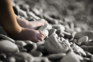 Children's foot on the sea stones