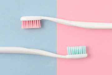 Close up of two plastic white toothbrushes with pink and blue bristle on pink and blue background. Free copy space. - 196018552