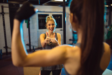 Two girls in fitness center. Girl holding thumbs up.