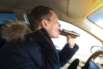 The driver of an alcoholic drinks cognac while driving a car. A man of 50 years is driving a car...
