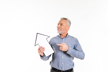 Smiling hopeful man holding arrow pointing at copy space isolated