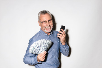 Happy lucky businessman holding smartphone and dollars