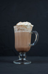 On a black background mug of hot cocoa with cream.