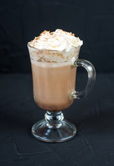 A glass of cocoa on black background with whipped cream.