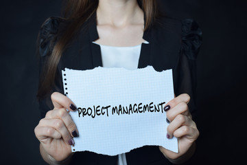 In the hands of a businessman a scrap of paper with the inscription:PROJECT MANAGEMENT