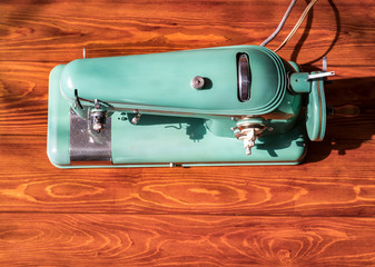 old electric sewing machine stands on a wooden lacquered table