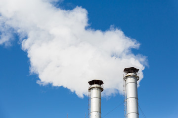 The smoke from the chimneys of the CHP. Pollution of the environment. Environmental disaster. Blue sky