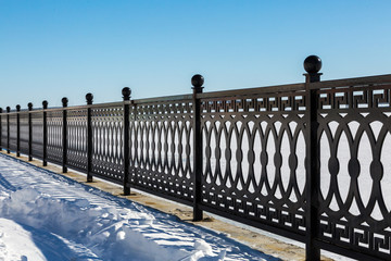 The metal fence on the waterfront. Winter day.