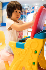Asian girl concentrate with her game in colorful playroom