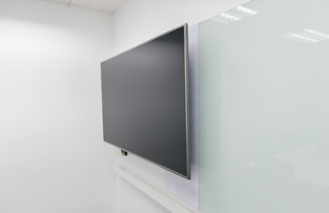 Fototapeta premium LED TV installed to the white wall of the meeting room with white board