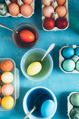 Dyeing eggs for Easter holidays, coloring with different color and tonality using food colorant over a gray concrete background