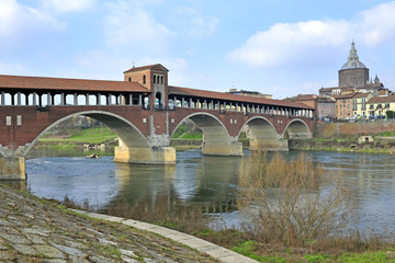 Fototapeta na wymiar Italy - Pavia - The Covered Bridge (also called Ponte Vecchio) on the ticino with the Cathedral of the city in the background