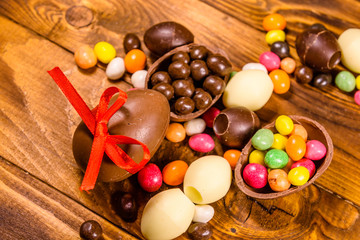 Chocolate easter eggs and multicolored candies on wooden table. Top view