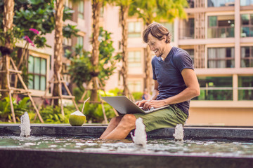 Fototapeta na wymiar Young freelancer working on vacation next to the swimming pool