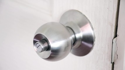 close-up of metal knob unlocking on white wooden door