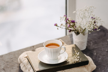 Fototapeta na wymiar Cup of tea, knit a blanket, flowers in the window