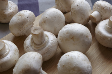 Fresh champignons on wooden cutting board, vegetarian food.