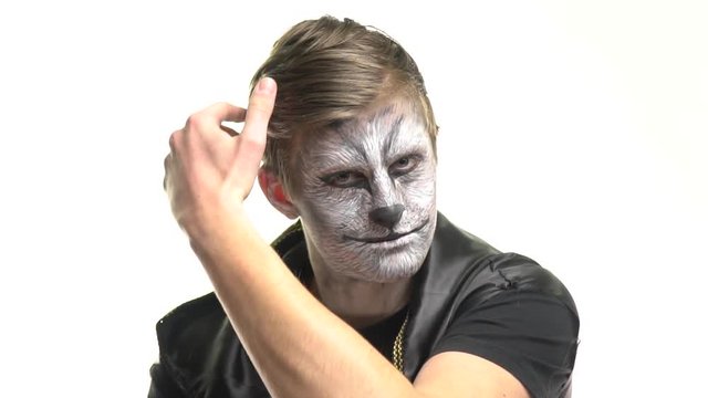 Body Art Raccoon on the face of a guy who adjusts his hair with his hair on his head. Animal Make up