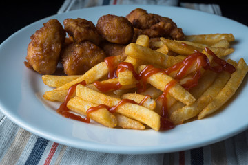 A plate of french fries and chicken 