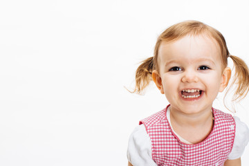 A very happy and excited toddler girl with ponytails laughing and showing teeth, isolated on white studio background