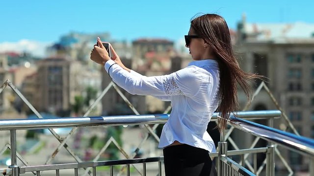 Woman records videos on smartphone. Businesswoman makes photos or records videos on his mobile phone. Beautiful girl with red cell phone
