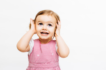 Preschool toddler girl with ponytails holding her ears and looking up isolated on white background