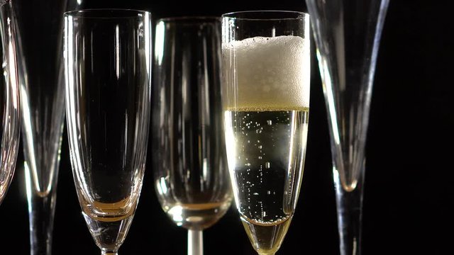 Closeup of bubbling glass of champagne in a glass against a black background.