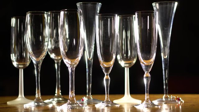 Slider shot pulling away of champagne glasses still life against black background.