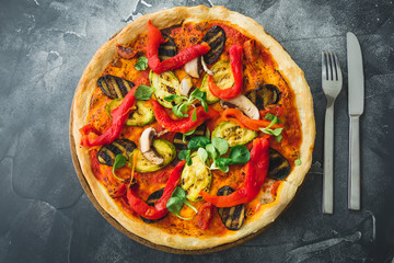 Vegetarian pizza with pepper, tomato, zucchini and mushrooms on dark background. Food background