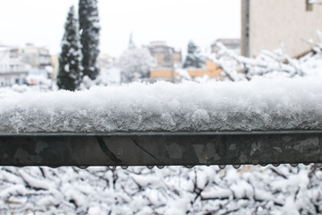 Snow on the handrail of an iron railing. Cold ice and snow in winter in the city, effects of climate change with low-altitude snow.