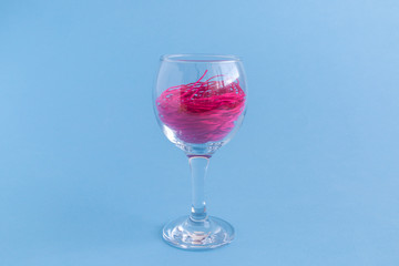 Red wine formed from red thread in glass isolated on blue creative concept.