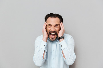 Portrait of an angry mature man dressed in shirt screaming