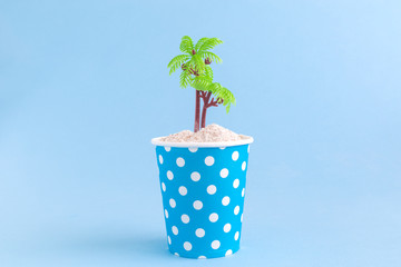 Paper cup with desert island travel minimalistic creative concept.