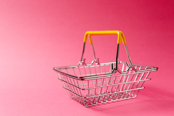 Close up of metal grocery basket for shopping in supermarket with raised handles and yellow plastic...