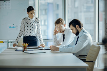 Shame on you. Strict young female boss frowning at her employees and scolding them in her office...