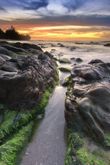 beautiful sunset with natural coastal rocks as foreground.