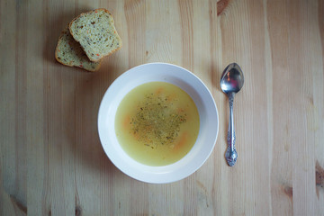 A plate of fresh soup in the plate placed on a wooden surface.