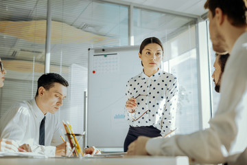 Fototapeta premium Important staff survey. Pleasant female boss conducting a daily meeting with her colleagues and listening to their feedback related to the changes in the contract