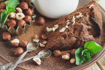 Piece of chocolate cake, mint leaves, hazelnuts and jar with milk