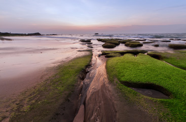 beautiful sunset with natural coastal rocks as foreground.